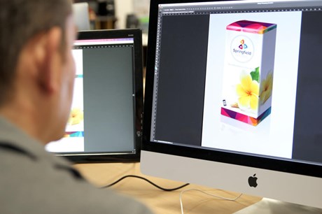 person looking at a 3d box rendering on a computer