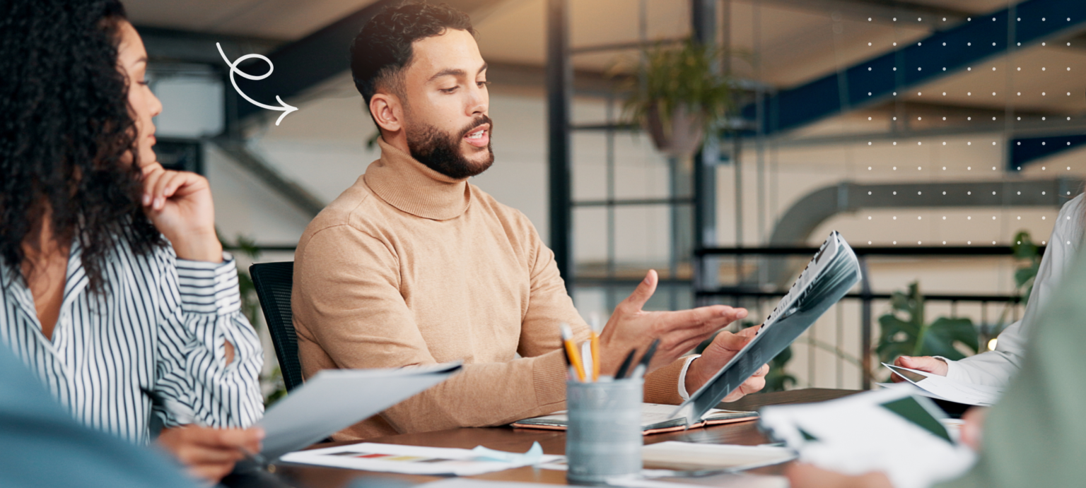 Image portraying co-workers at a desk with papers, discussing something